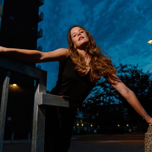 Portrait of a young woman in London Fields in East London at dusk, as wind blows through her blond hair.