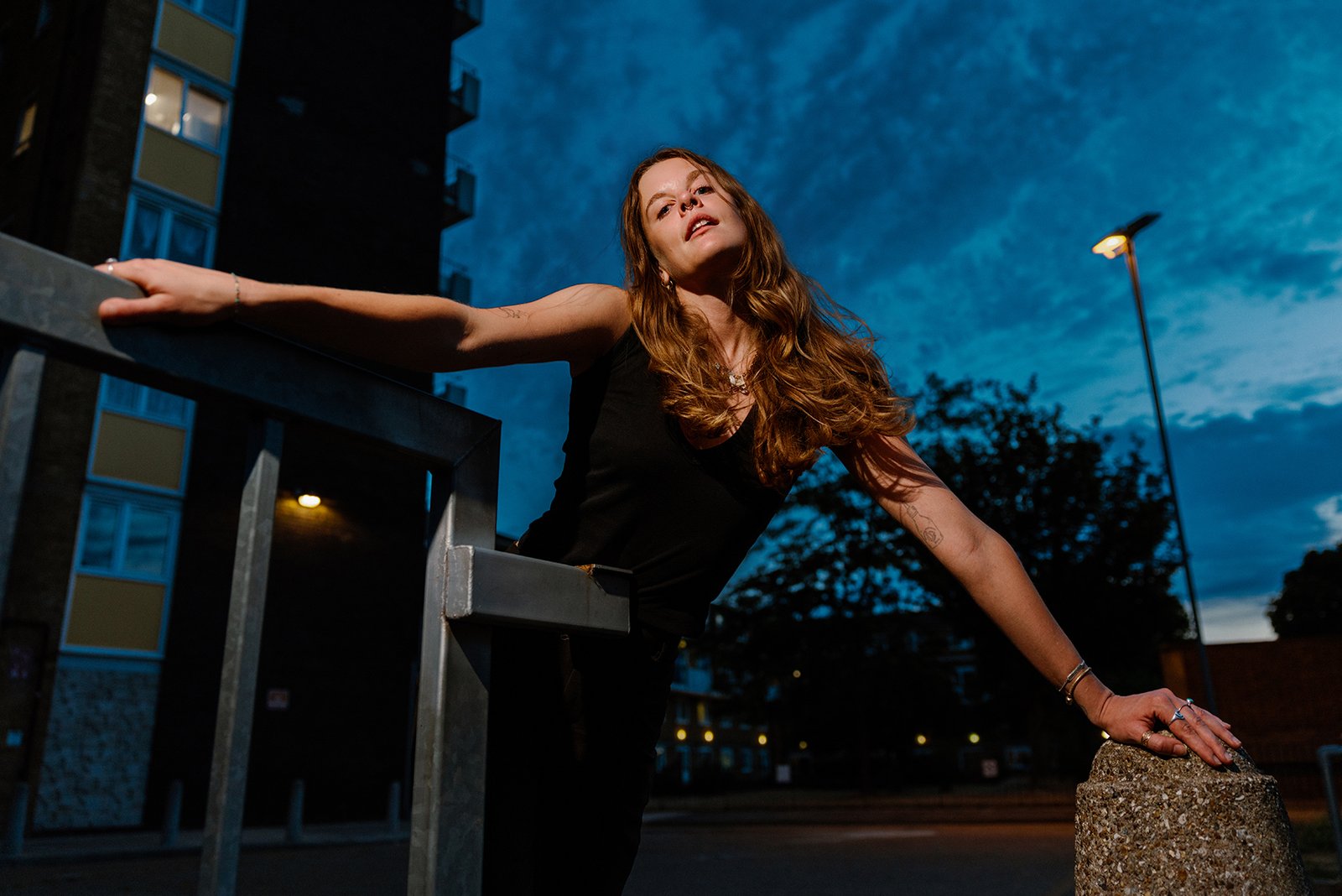 Portrait of a young woman in London Fields in East London at dusk, as wind blows through her blond hair.