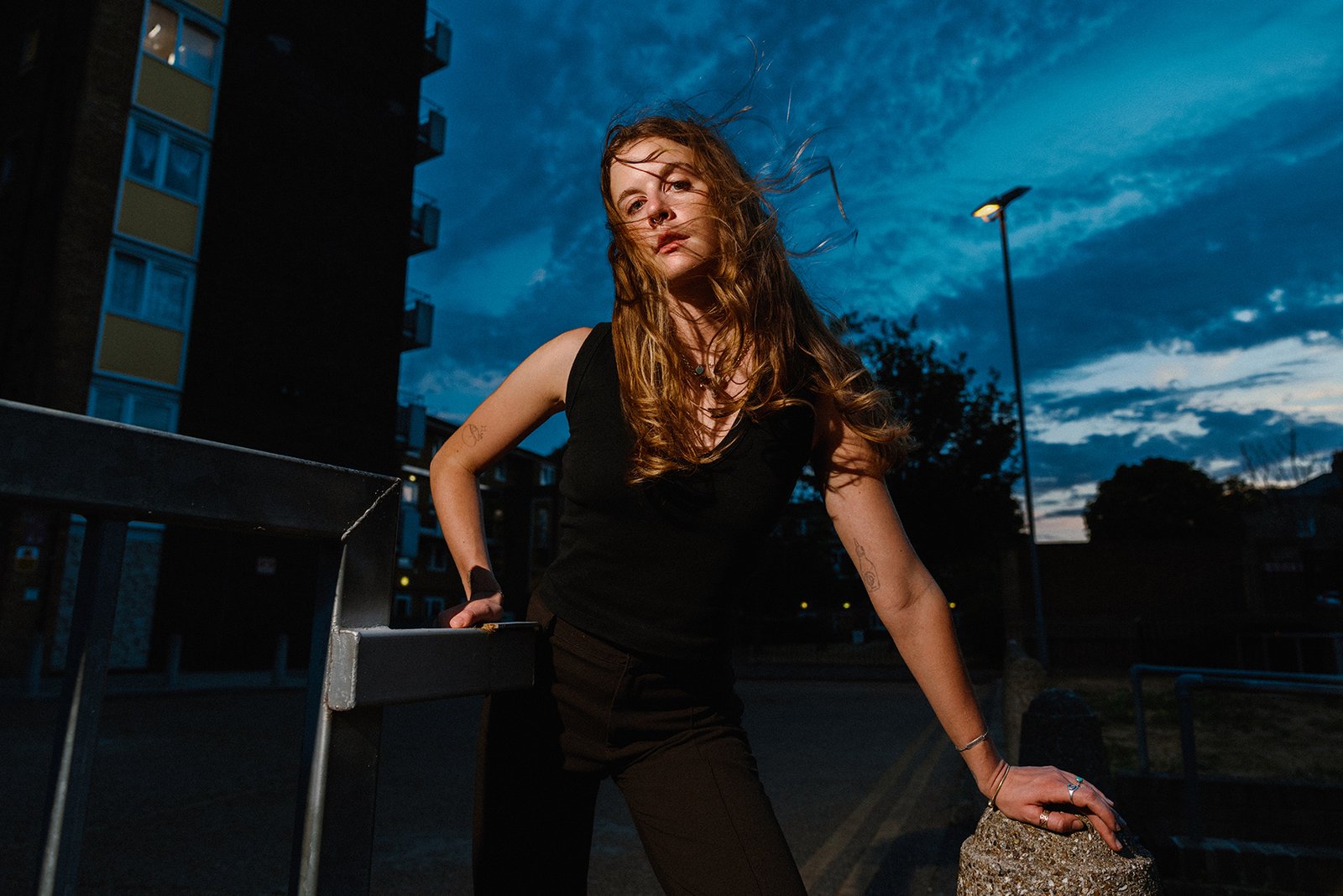 Portrait of a young woman in London Fields in East London at dusk, as wind blows through her blond hair.